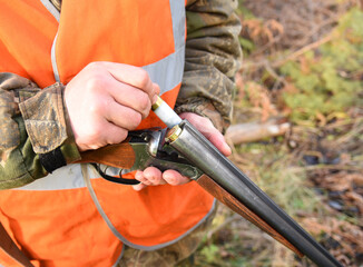 Shotgun in hunter hand. Hunter loads Cartridge (firearms) with shot into a double-barreled shotgun....