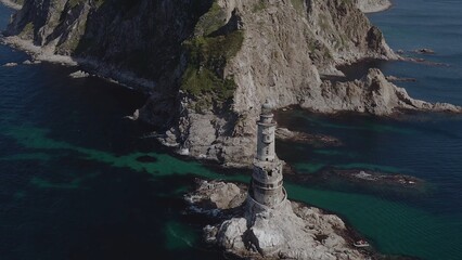 Lone lighthouse located near to ocean coast with rocks water shot by drone aerial view background theme above ground amazing picture masterpiece nature building architecture perfect 