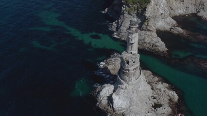 Lone lighthouse located near to ocean coast with rocks water shot by drone aerial view background theme above ground amazing picture masterpiece nature building architecture perfect 