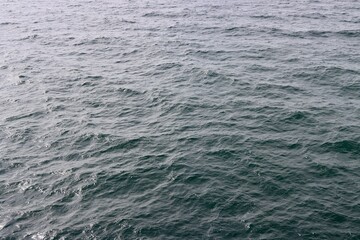 Smooth surface of far open Baltic sea. Deep blue water, reflections of sun light. Photo taken from ship