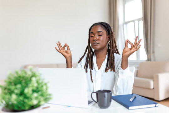 Calm African female executive meditating taking break at work for mental balance, mindful businesswoman feeling relief and no stress doing yoga at work ignoring avoiding stressful job