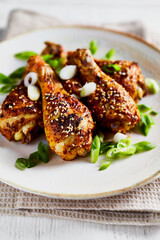 Roasted chicken legs with sesame seeds and spring onion on the plate