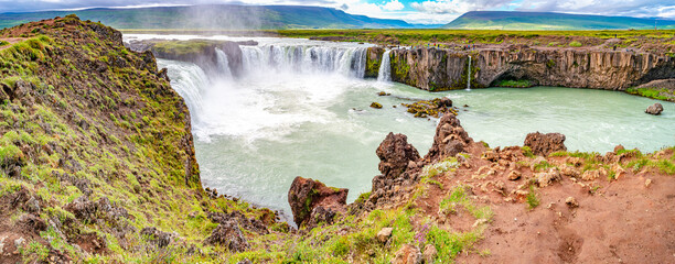 Scenic panoramic view of popular tourist attraction waterfall Godafoss in Iceland with tourists watching the sightseeing, summer, dramatic sky.