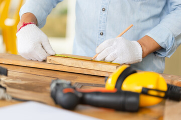 Carpenter working with equipment on wooden table in wood workshop, man doing woodwork in carpentry shop
