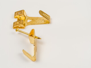 close up flat lay image of a pair of single hook brass  metal wall mounted picture hooks