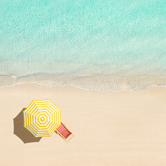 Top view of sunbed, lounge, yellow umbrella, SUP board for surfing on the shore on tropical...