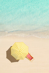 Top view of sunbed, lounge, yellow umbrella, SUP board for surfing on the shore on tropical Seychelles sand beach. Blue, turquoise transparent water surface of ocean, sea. Aerial, drone view. vertical - 511499058