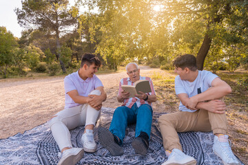 Abuelo leyendo un libro a sus nietos, sentados en el campo, con expresión alegre, en un día...