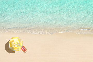 Aerial view of wooden sunbed, lounge, yellow umbrella on sandy beach. Summer and travel concept....