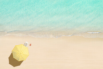 Fototapeta na wymiar Aerial view of sunbed, lounge, flip flops, yellow umbrella on sandy beach. Summer and travel concept. Blue, turquoise transparent water surface of ocean, sea, lagoon. Aerial, drone view
