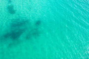 Blue, turquoise transparent water surface of ocean, sea, lagoon. Horizontal background. Top view of sand beach. Aerial, drone view