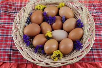 chicken eggs decorated with dried flowers (statica, kermek) in a wicker basket on a bright tablecloth