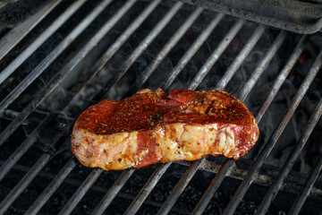  Raw meat beef steak  grilling on rack charcoal stove with smoke on black background.