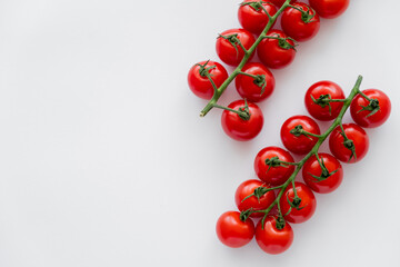 Top view of fresh ripe cherry tomatoes on branches on white background.