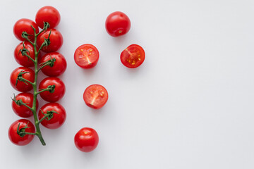 Fototapeta na wymiar Top view of whole and cut cherry tomatoes on white background.