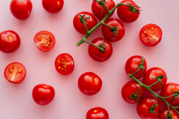 Top view of ripe cherry tomatoes on branches on pink background.