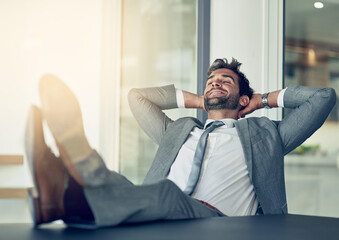 Taking a break from business. Shot of a businessman leaning back in his chair with his feet on a...