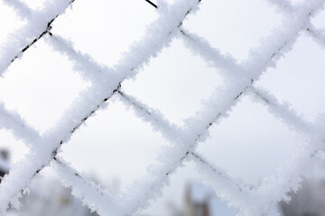 Close-up of snow covered mesh net with bright blue sky in background confining restricted area....