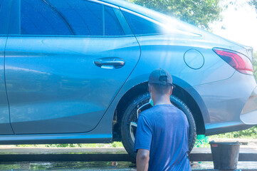 Staff or car washer at car care service washing a car of customer