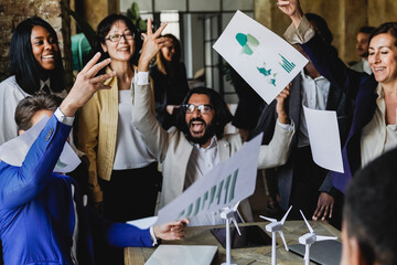 Multiethnic business people celebrating renewable energy project success together throwing...