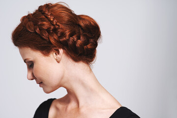 Soft and romantic. Studio shot of a beautiful redhead woman with a braided up-do posing against a gray background. - obrazy, fototapety, plakaty