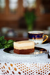 A piece of cake and a cup with a drink on the table.