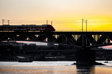 Traffic on the railway bridge. Train at sunset.