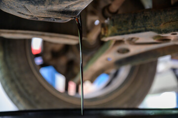 Close-up shot of old car engine oil draining from engine to change new oil at the service center or...