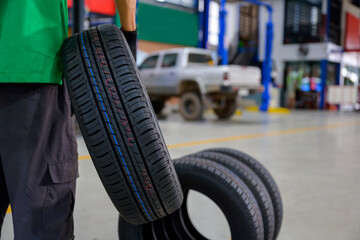 male tire changer In the process of bringing 4 new tires that are in stock in order to change the wheels of the car at a service center or an auto repair shop for the automobile industry