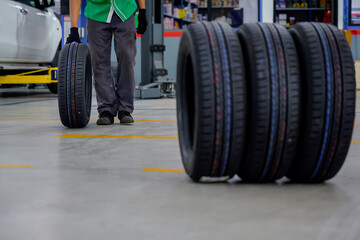Male car mechanic changing tire In the process of bringing 4 new tires in the tire shop to replace...