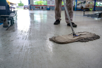 Car mechanic cleaning the car repair area Use an epoxy mop in an auto repair shop.