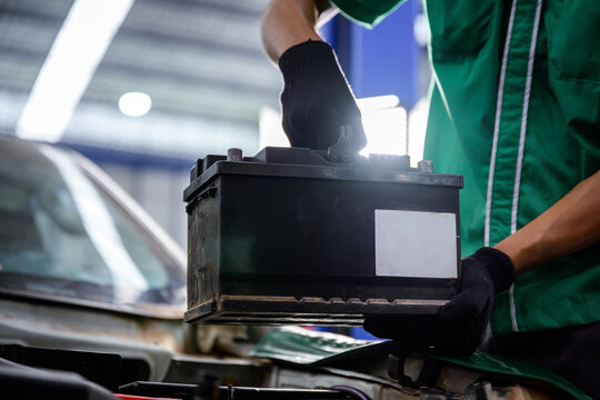 Close-up of a car mechanic in a service center picking up a new battery to replace the car. for cars that use the service Replace the battery at the store