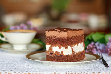 A piece of cake and a cup with a drink on the table.