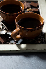 fresh black coffee in a cups and chocolate on blackboard, closeup vertical