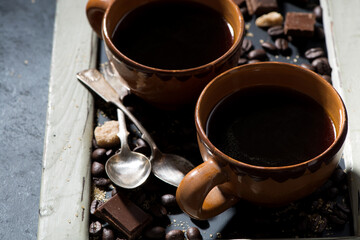 fresh black coffee in a cups, sugar and chocolate on blackboard, closeup