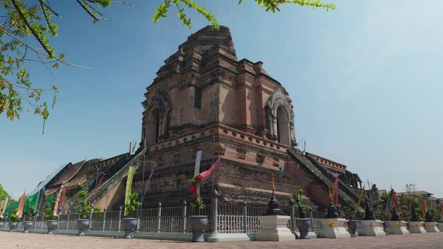 4K Cinematic landscape footage of the buddhist temple monument of Wat Chedi Luang in the old town of Chiang Mai, North Thailand on a sunny day.