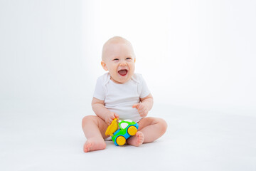 Fototapeta na wymiar baby boy in a white bodysuit is sitting playing with toy cars on white background