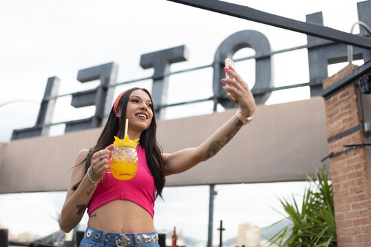 Happy beautiful young woman enjoys a relaxing time on the terrace of a bar and take a selfie