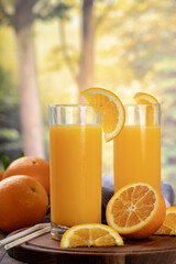 Two glasses of orange juice with summer rural background