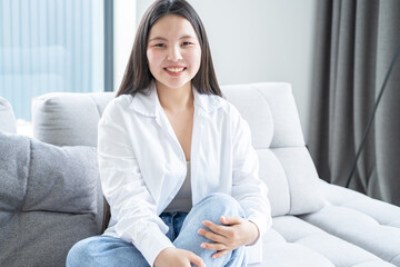 portrait of beautiful smiling young asian woman with long dark hair in white shirt at modern home