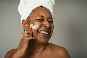 Happy African senior woman having skin care spa day - People wellness lifestyle concept
