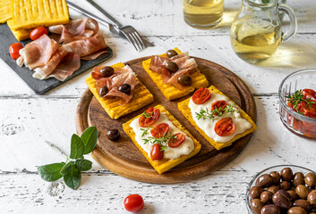 Antipasto with grilled polenta topped with stracchino cheese, tomatoes, herbs, speck and olive. Top...