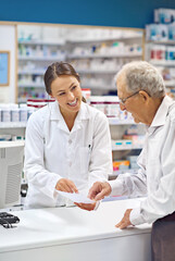 Filling prescriptions with a smile. Shot of a young pharmacist helping an elderly customer at the...