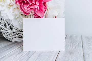 Empty greeting card with copy space on the table with bouquet of pink peonies. 