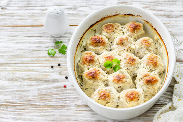 Sour cream turkey  meatballs in baking dish on wooden background. Top view, copy space, flat lay.