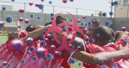 Animation of virus cells and biohazard symbol over diverse male rugby players teaming up - Powered by Adobe