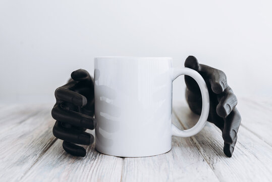 White cup of coffee on a table in plastic hands, mockup 
