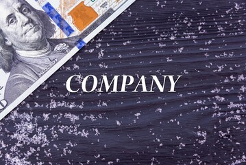 COMPANY - word (text) on a dark wooden background, money, dollars and snow. Business concept (copy space).