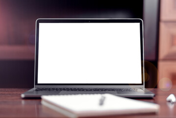 Laptop with blank screen on table with notebook and pen on it