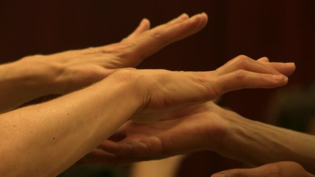 Several hands hovering one on top of the other, in an exercise of breathing and chanting. Rehearsal